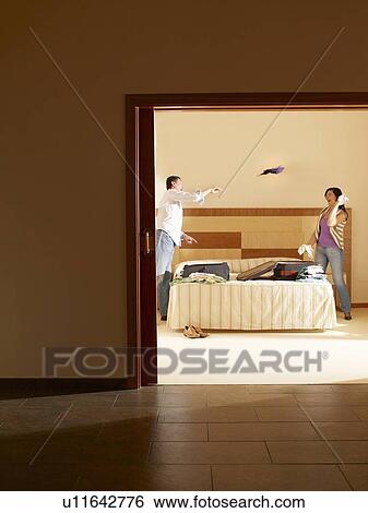 Mature couple in hotel room, man throwing clothing over bed View Large Photo Image Stock Photograph - Mature couple in hotel room, man throwing clothing over bed. Fotosearch