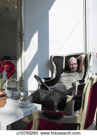Mature man relaxing in armchair in cafe, smiling, portrait View Large Photo Image Stock Photography - Mature man relaxing in armchair in cafe, smiling, portrait. Fotosearch