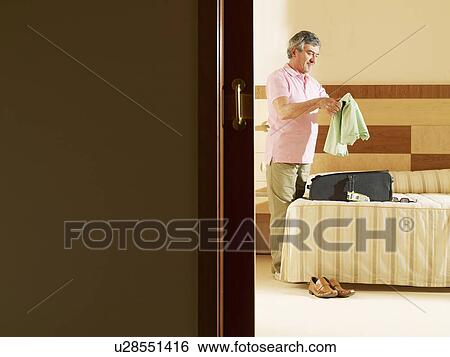 Senior man unpacking clothes in hotel room View Large Photo Image Stock Photograph - Senior man unpacking clothes in hotel room. Fotosearch