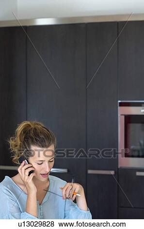 Stock Photo - Woman in kitchen talking on phone.. Fotosearch