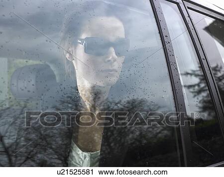 Stock Image - Woman looking through her car window. Fotosearch
