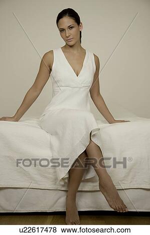 Portrait of a woman sitting on a bed View Large Photo Image Stock Photo - Portrait of a woman sitting on a bed. Fotosearch