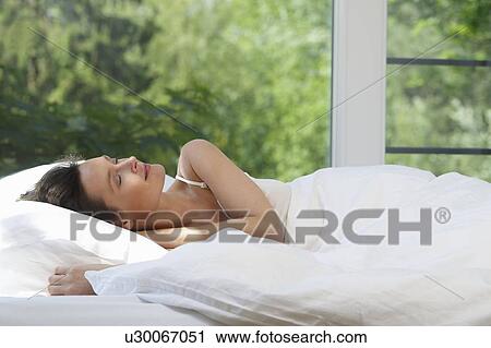 Stock Image - Woman in bed, in the morning. Fotosearch