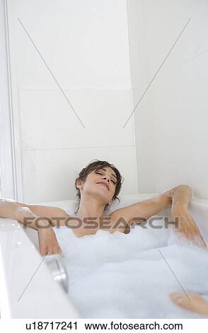 Stock Image - Woman relaxing in bubble bath. Fotosearch