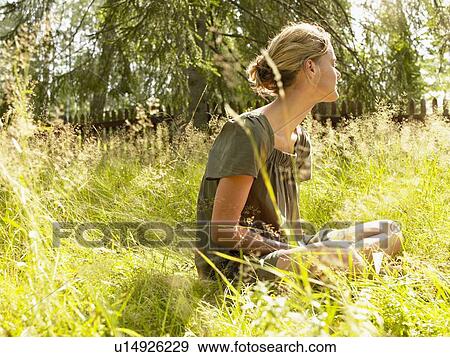 Woman sitting in the grass relaxing. View Large Photo Image Stock Photo - Woman sitting in the grass relaxing.. Fotosearch