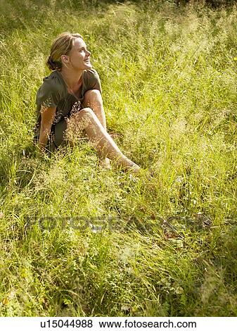 Woman sitting in the grass smiling. View Large Photo Image Stock Photo - Woman sitting in the grass smiling.. Fotosearch