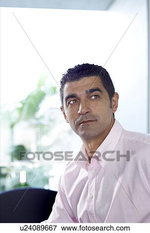 Stock Photo - Businessman wearing open neck shirt in office. Fotosearch