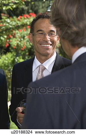 Businessmen drinking wine in a garden View Large Photo Image Picture - Businessmen drinking wine in a garden. Fotosearch