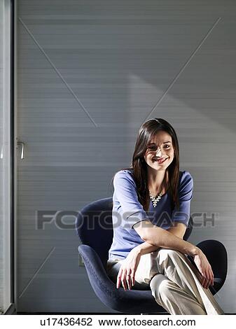 Businesswoman sitting in office, smiling, portrait View Large Photo Image Stock Image - Businesswoman sitting in office, smiling, portrait. Fotosearch