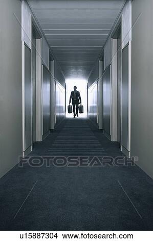 Picture - Man carrying suitcases in a hallway. Fotosearch