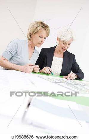 Two women studying some papers View Large Photo Image Stock Photograph - Two women studying some papers. Fotosearch