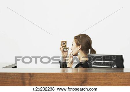 Woman at a desk with a compact mirror View Large Photo Image Stock Photo - Woman at a desk with a compact mirror. Fotosearch