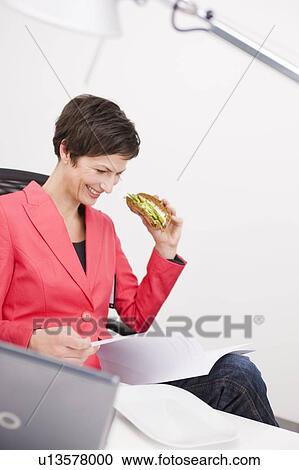 Woman eating sandwich at her office View Large Photo Image Stock Image - Woman eating sandwich at her office . Fotosearch