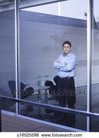 Young businessman standing at window in office, portrait View Large Photo Image Stock Photo - Young businessman standing at window in office, portrait. Fotosearch