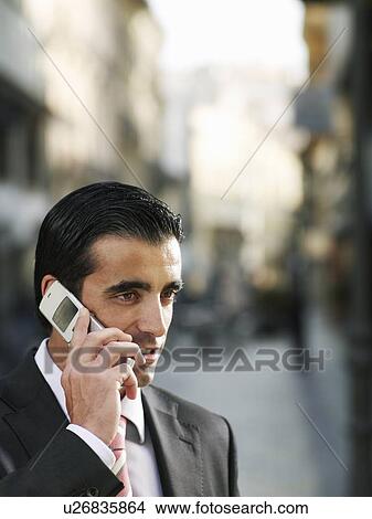 Young businessman using mobile phone in street, close-up View Large Photo Image Picture - Young businessman using mobile phone in street, close-up. Fotosearch