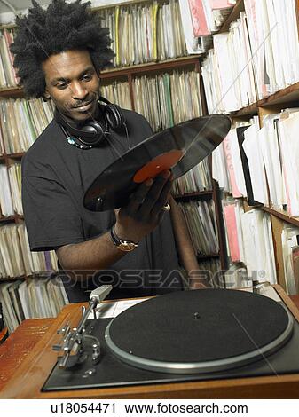 Male DJ holding record in music shop, smiling View Large Photo Image Stock Image - Male DJ holding record in music shop, smiling. Fotosearch