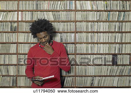 Stock Image - Man looking at compact disc in music shop. Fotosearch