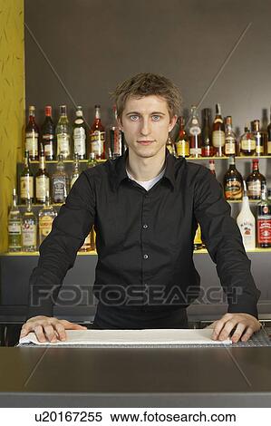 Stock Photography - Portrait of young barman behind his bar. Fotosearch