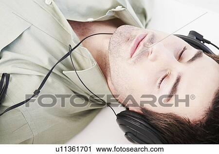 Reclined male relaxes with headphones View Large Photo Image Stock Image - Reclined male relaxes with headphones. Fotosearch