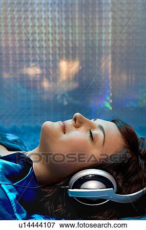 Stock Photo - Woman laying on floor with head set. Fotosearch