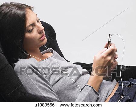 Stock Image - Woman listening to music on mp3 player. Fotosearch