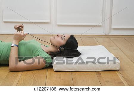 Woman lying on floor listening to music View Large Photo Image Stock Photograph - Woman lying on floor listening to music. Fotosearch