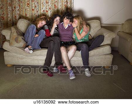 Stock Image - Women, sitting on sofa, looking sad. Fotosearch