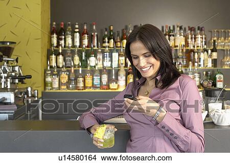 Young woman texting leaning at bar View Large Photo Image Picture - Young woman texting leaning at bar. Fotosearch