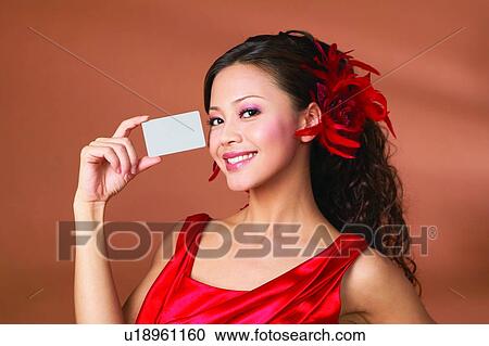 Stock Image - Showing, Happiness, Asian Ethnicity, Glamour, Holding, Looking At Camera, Colored Background. Fotosearch