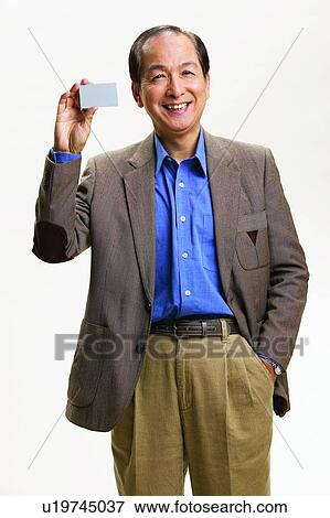 Stock Photo - Standing, Looking At Camera, Show Card, Mature Adult, Asian Ethnicity. Fotosearch