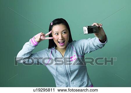 Stock Image - Cheerful, Colored Background, Digital Camera, Waist-Up, Holding, Self Portrait Photography. Fotosearch