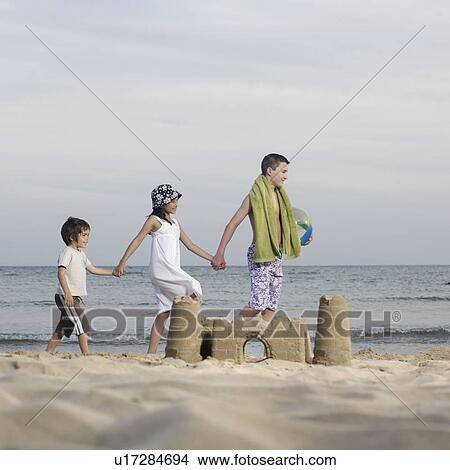 Picture - Children holding hands on beach. Fotosearch