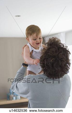 Stock Photograph - Father holds and looks at baby. Fotosearch