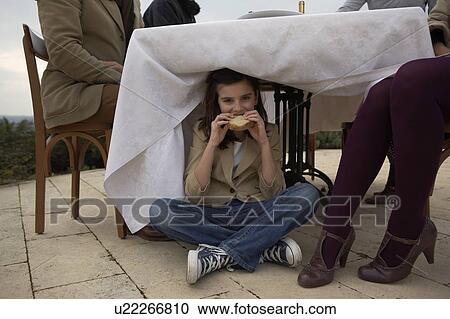 Girl (9-11) eating bread under dinner table View Large Photo Image Stock Image - Girl (9-11) eating bread under dinner table. Fotosearch