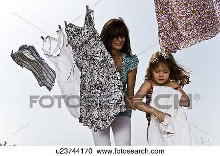 Girl helping mother fold clothes View Large Photo Image Stock Image - Girl helping mother fold clothes. Fotosearch
