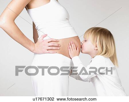 Stock Image - Girl kissing her mother's pregnant belly. Fotosearch