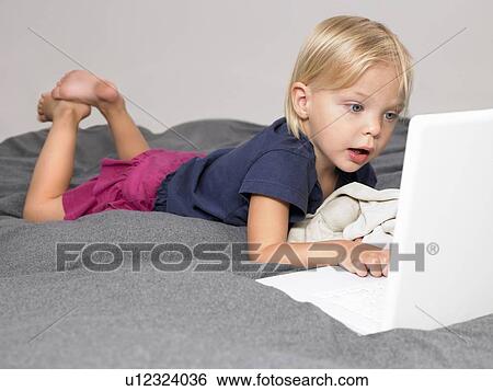 Little girl looking at a laptop View Large Photo Image Stock Photograph - Little girl looking at a laptop. Fotosearch