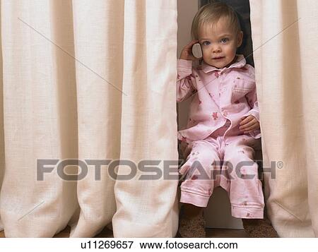 Stock Photo - Little girl on the phone behind curtain.. Fotosearch