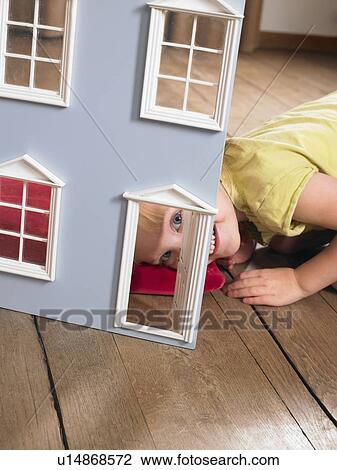 Stock Image - Little girl playing with a doll house. Fotosearch