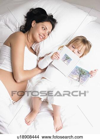 Picture - Mother and daughter in bed, reading. Fotosearch