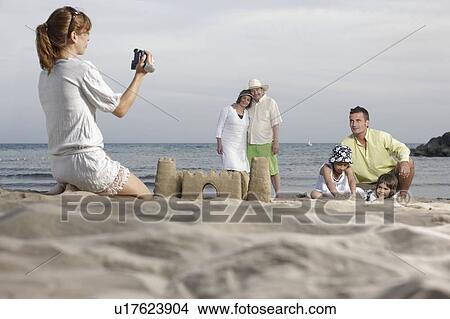 Mother taking video of family on beach View Large Photo Image Picture - Mother taking video of family on beach. Fotosearch