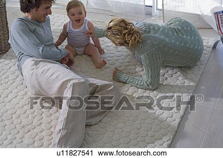 Parents play with baby on carpet View Large Photo Image Stock Image - Parents play with baby on carpet. Fotosearch