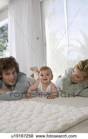 Stock Photo - Parents with baby happy on carpet. Fotosearch