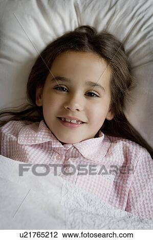 Stock Image - Portrait of a young girl in bed.. Fotosearch