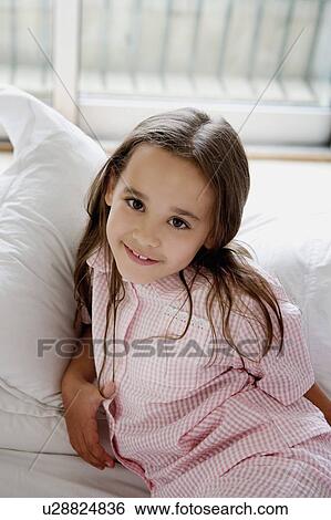 Stock Photograph - Portrait of a young girl laying on a bed.. Fotosearch