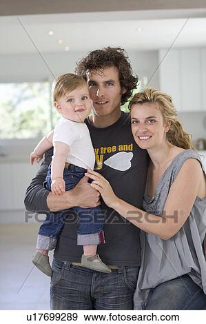 Stock Photo - Portrait parents with baby in home. Fotosearch