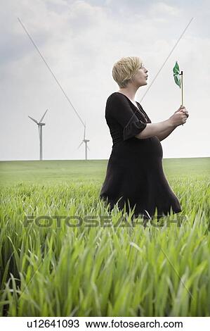 Stock Image - Pregnant woman blowing a windmill. Fotosearch