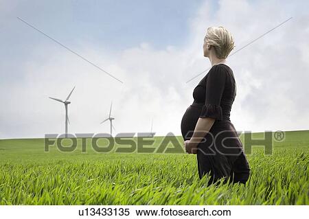 Pregnant woman looking at wind turbines View Large Photo Image Stock Photography - Pregnant woman looking at wind turbines. Fotosearch