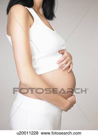 Pregnant woman touching her stomach View Large Photo Image Stock Photo - Pregnant woman touching her stomach. Fotosearch