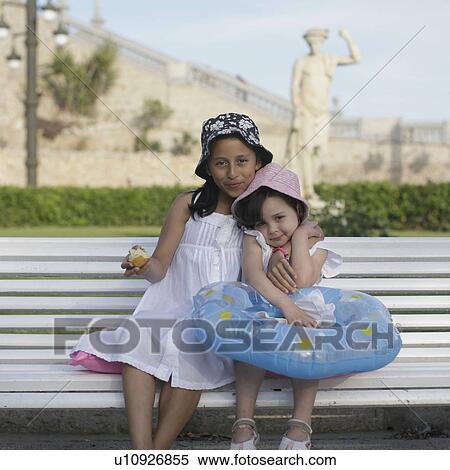 Stock Photography - Two young girls sitting on bench. Fotosearch